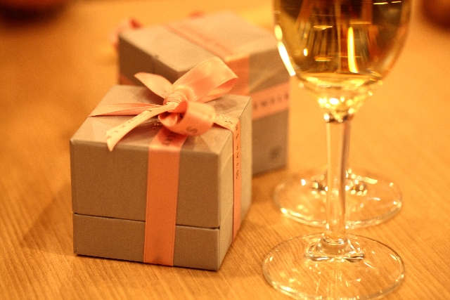 シャンパンが入ったグラスとリボンの巻かれたプレゼントボックスの写真