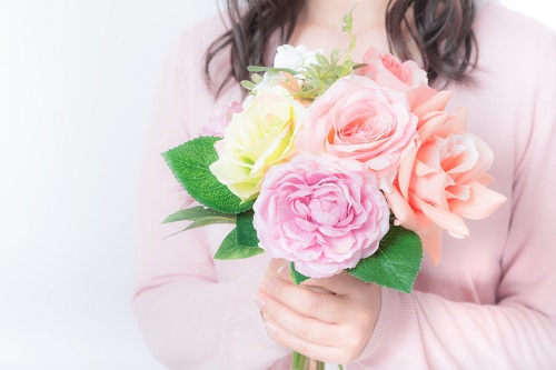 ピンクの花束を胸元に抱えた女性の写真