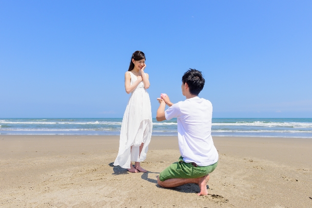 海辺でプロポーズするカップル