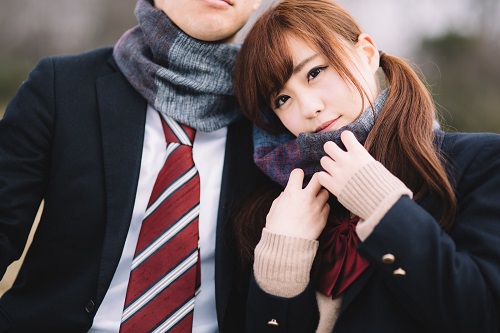 男子学生と一緒にマフラーを巻く女子高生の写真