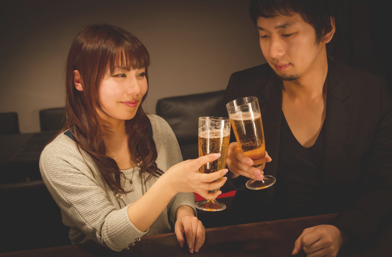 バーでビールジョッキを持って乾杯をする男女