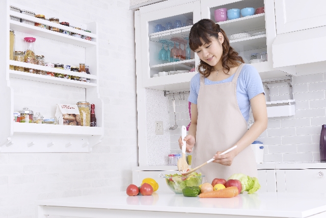 エプロンをつけて料理をする女性